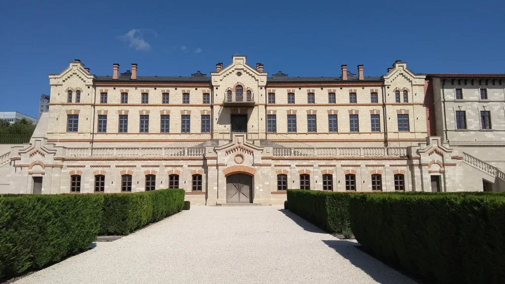 Light stone facade of Castel Mimi in Bulboaca with a path between trimmed hedges