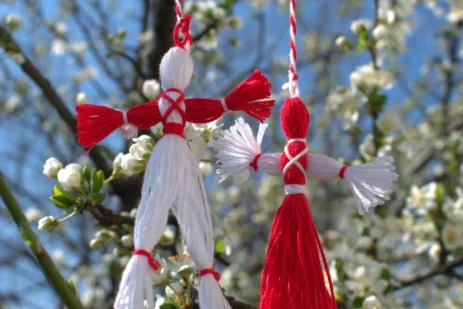 Mărțișor charms on red-and-white strings against blossoming branches