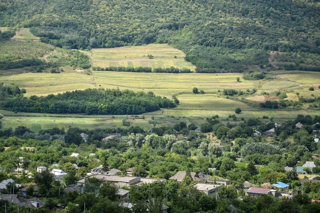 Peisaj rural deluros în raionul Hîncești, Republica Moldova, cu câmpuri, livezi și un sat